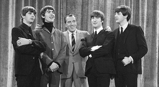 The Beatles flank Ed Sullivan on the stage of The Ed Sullivan Show in February 1964